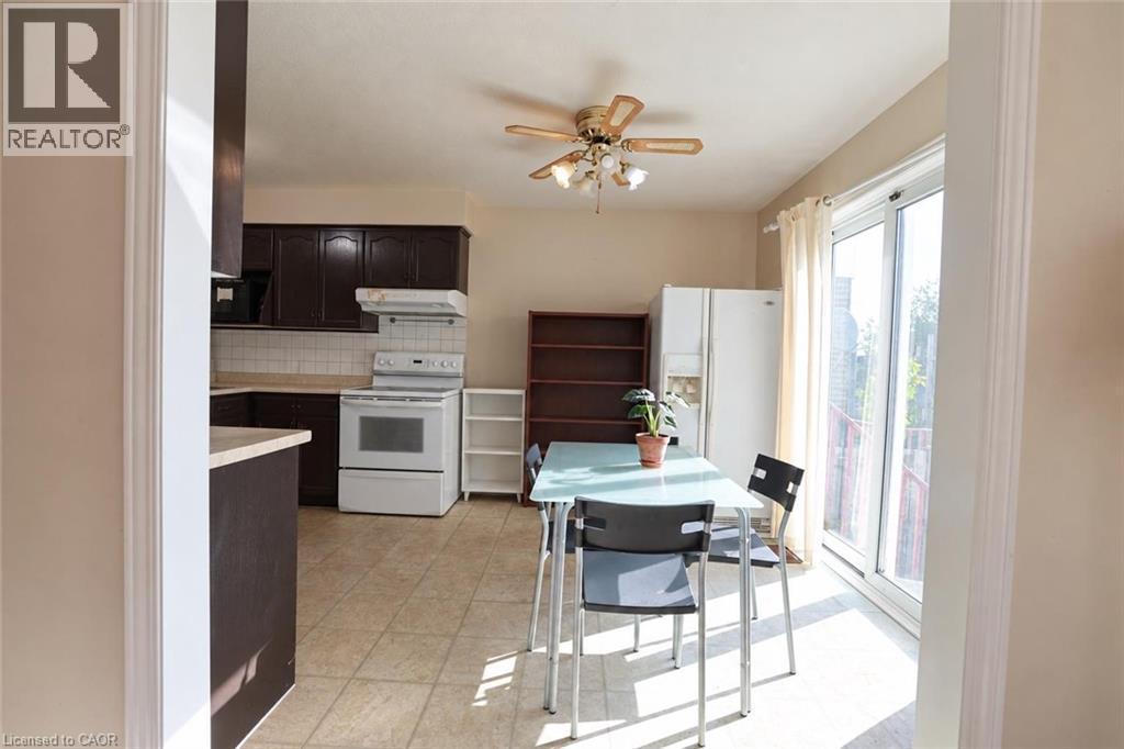 Kitchen with dark wood-finish cabinetry, white appliances, and tiled flooring - 95 Resurrection Drive, Kitchener, ON