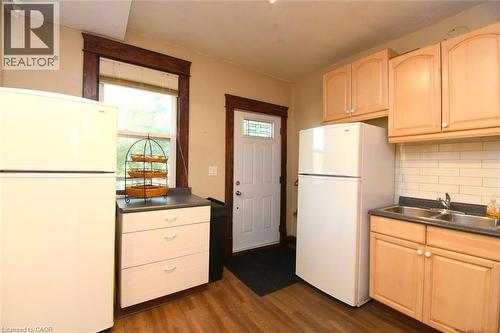 Wood-finish flooring with a white entry door featuring decorative glass - 734 King Street W, Hamilton, ON 