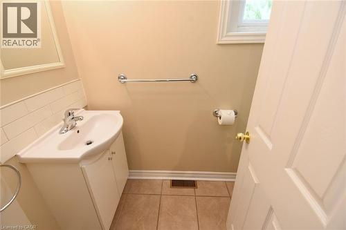 White paneled door with a brass knob, ceramic tile flooring, and a white sink vanity with chrome faucet - 734 King Street W, Hamilton, ON 