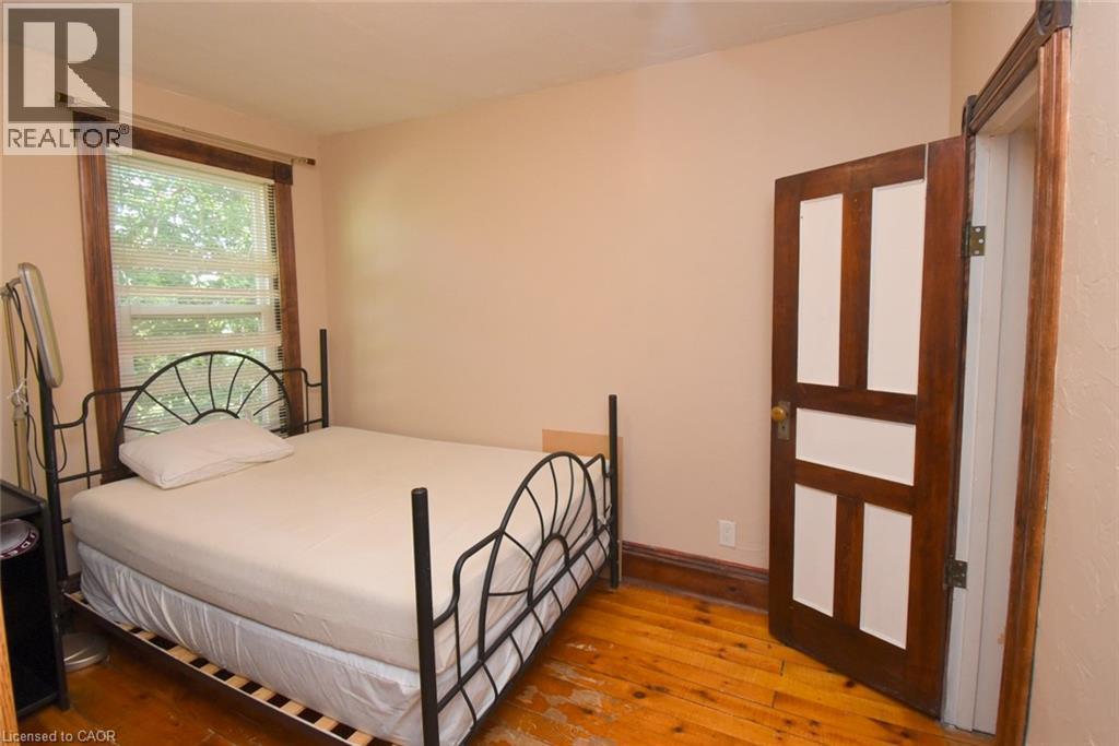 Wood-finish flooring with a natural grain, white wall paint, and a classic paneled door - 734 King Street W, Hamilton, ON