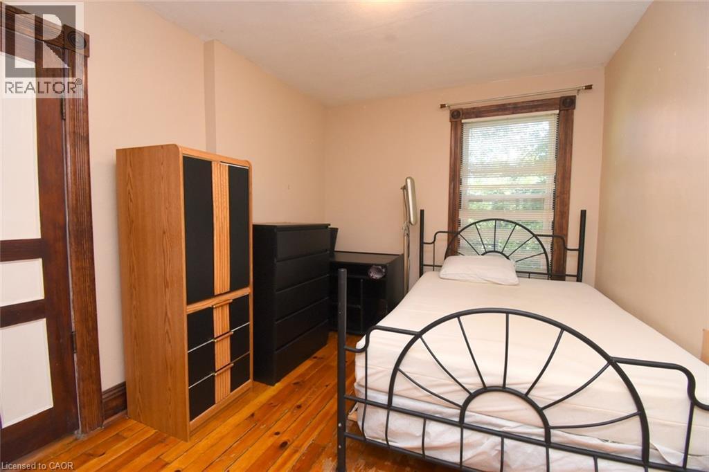 Hardwood flooring, painted walls, window with blinds, and a paneled wood door with decorative trim - 734 King Street W, Hamilton, ON
