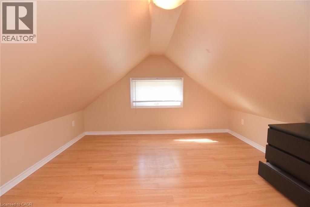 Sloped ceiling, wood-finish flooring, white trim, recessed window, and flush mount lighting - 734 King Street W, Hamilton, ON