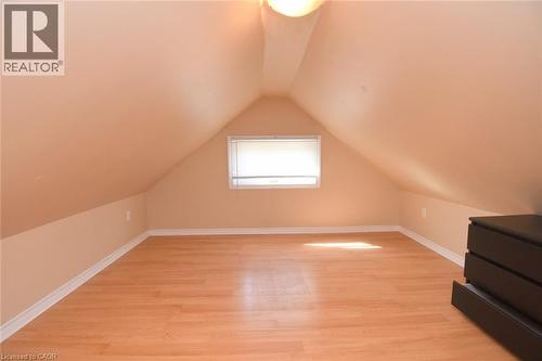 Sloped ceiling, wood-finish flooring, white trim, recessed window, and flush mount lighting - 734 King Street W, Hamilton, ON 