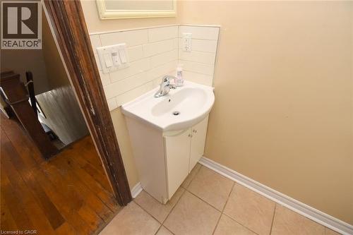 Pedestal sink with cabinet storage, tile backsplash, and tile flooring - 734 King Street W, Hamilton, ON 