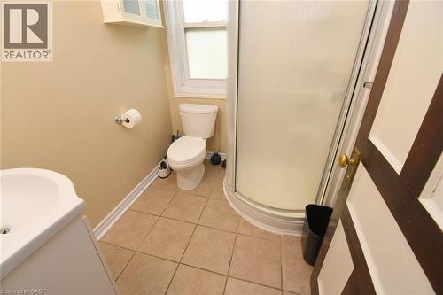 Bathroom featuring a corner shower enclosure, window, pedestal sink, and tiled flooring - 734 King Street W, Hamilton, ON 