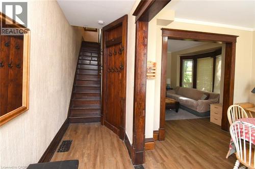Wood-finish flooring throughout, dark wood-stained trim and door frames, built-in coat rack, and a bay window in an adjacent room - 734 King Street W, Hamilton, ON 