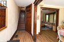 Wood-finish flooring throughout, dark wood-stained trim and door frames, built-in coat rack, and a bay window in an adjacent room - 734 King Street W, Hamilton, ON 