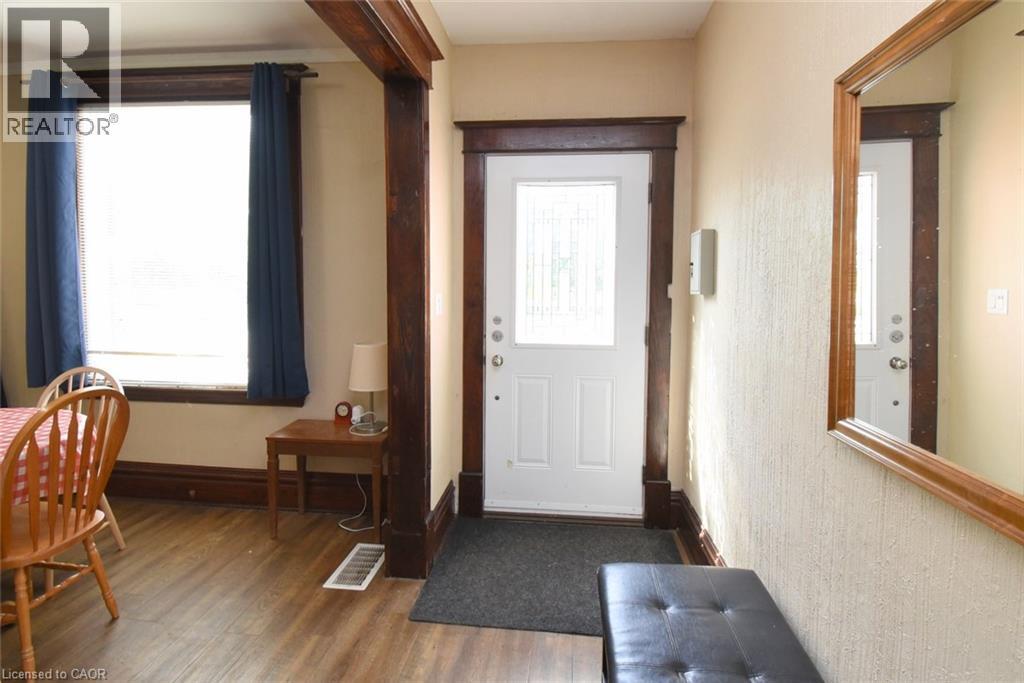 Entryway with wood-finish flooring, white paneled door with decorative glass, and a full-length wall mirror - 734 King Street W, Hamilton, ON