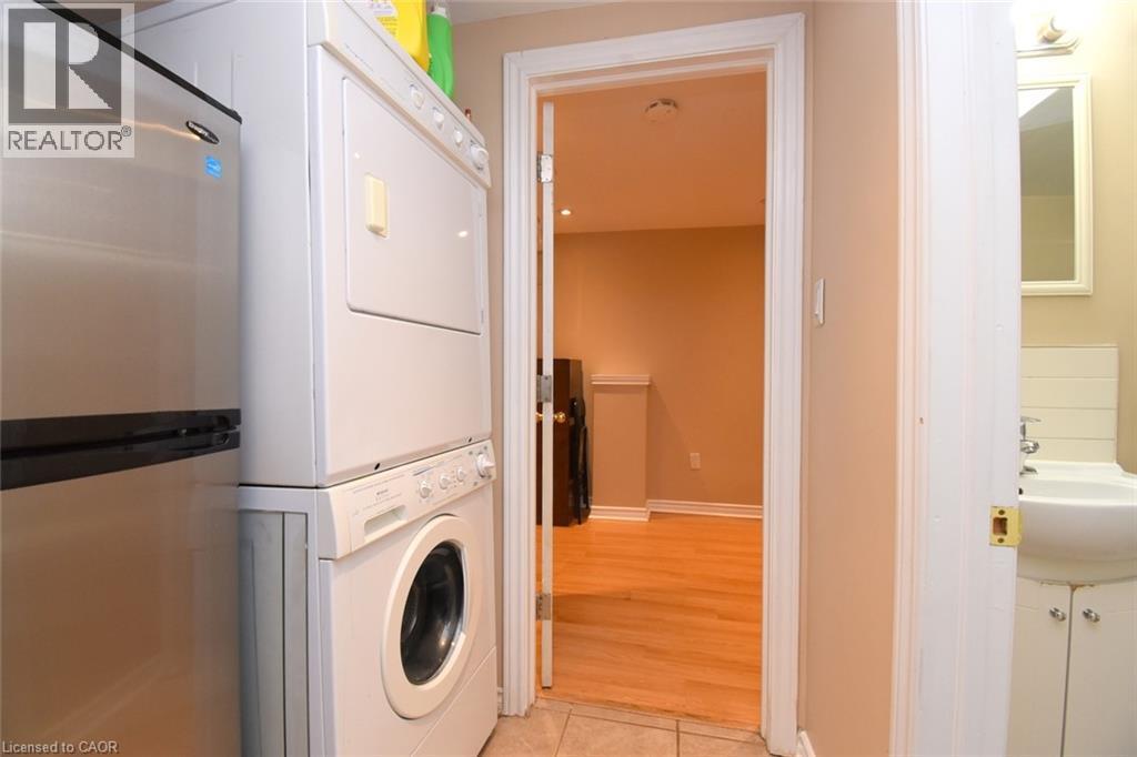 Stainless steel refrigerator with a stacked washer and dryer unit - 734 King Street W, Hamilton, ON