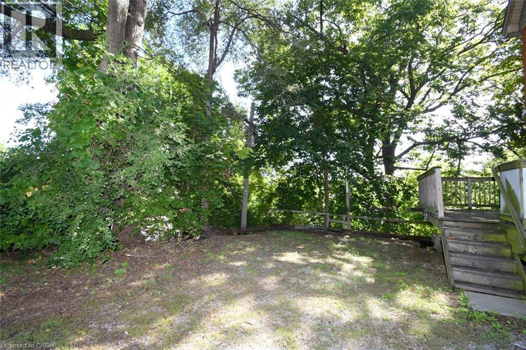 Expansive exterior featuring mature trees, a multi-level wood deck, and wood fencing - 734 King Street W, Hamilton, ON