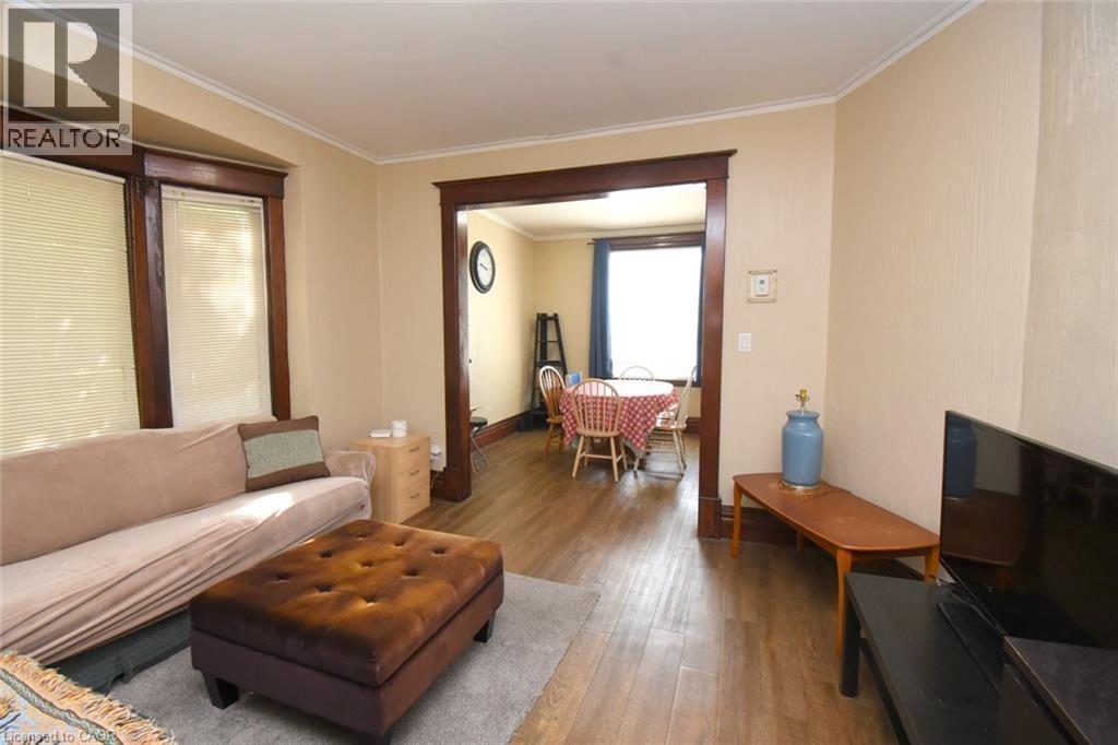 Hardwood-look flooring throughout, cased openings with dark wood trim, and crown molding - 734 King Street W, Hamilton, ON
