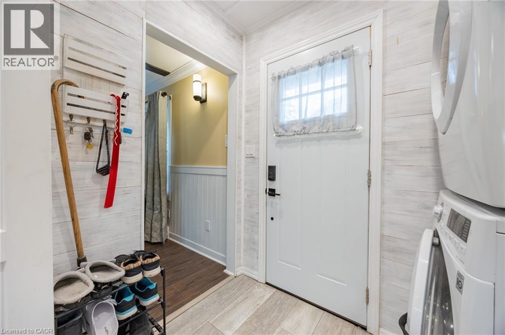 Shiplap wall paneling, light wood-finish flooring, white paneled door with window, and a built-in light fixture - 102 Stewart Avenue, Cambridge, ON