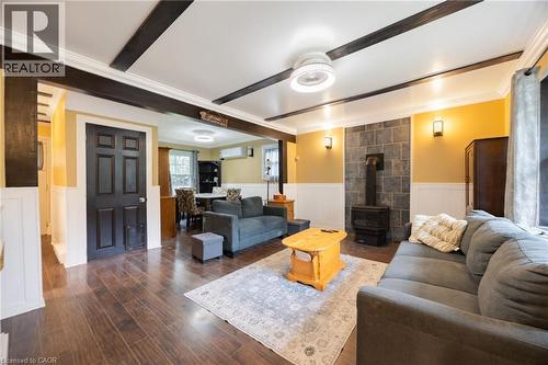 Wood-finish flooring, exposed ceiling beams, wainscoting, stone-clad wall with a gas fireplace, and wall sconces - 102 Stewart Avenue, Cambridge, ON 