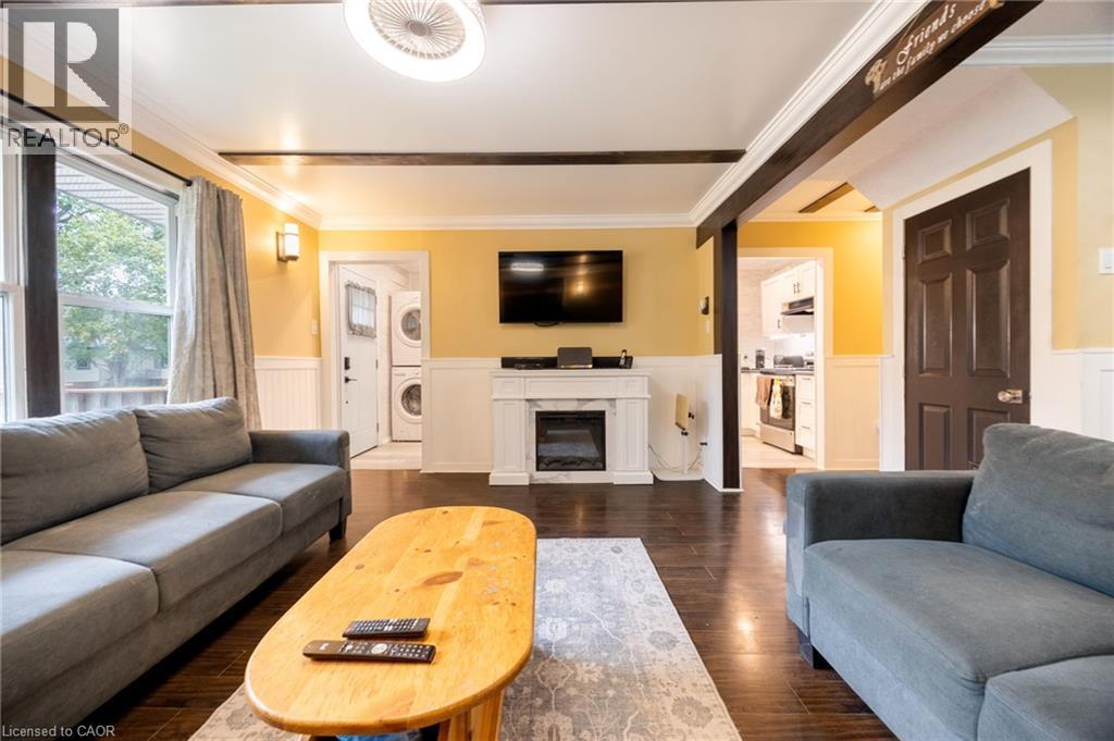 Living area featuring dark wood-finish flooring, white wainscoting, and a gas fireplace - 102 Stewart Avenue, Cambridge, ON