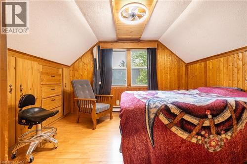 Sloped ceiling room featuring wood-finish wall paneling, built-in cabinetry with drawers, wood-finish flooring, and a ceiling fan with integrated lighting - 102 Stewart Avenue, Cambridge, ON 