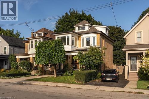 Brick exterior with white trim, multiple bay windows, dormer windows, and a paved driveway - 50 Norway Avenue, Hamilton, ON 