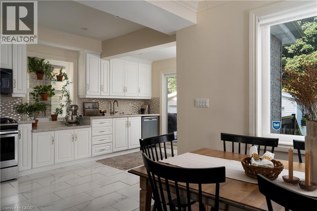 White shaker-style cabinetry, mosaic tile backsplash, stainless steel appliances, light-toned countertop, and large format floor tiling - 50 Norway Avenue, Hamilton, ON