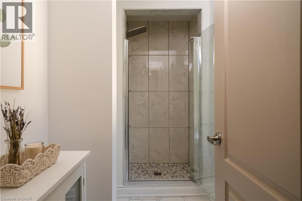 Walk-in shower with full-height tile surround, glass enclosure, and pebble-style floor - 50 Norway Avenue, Hamilton, ON