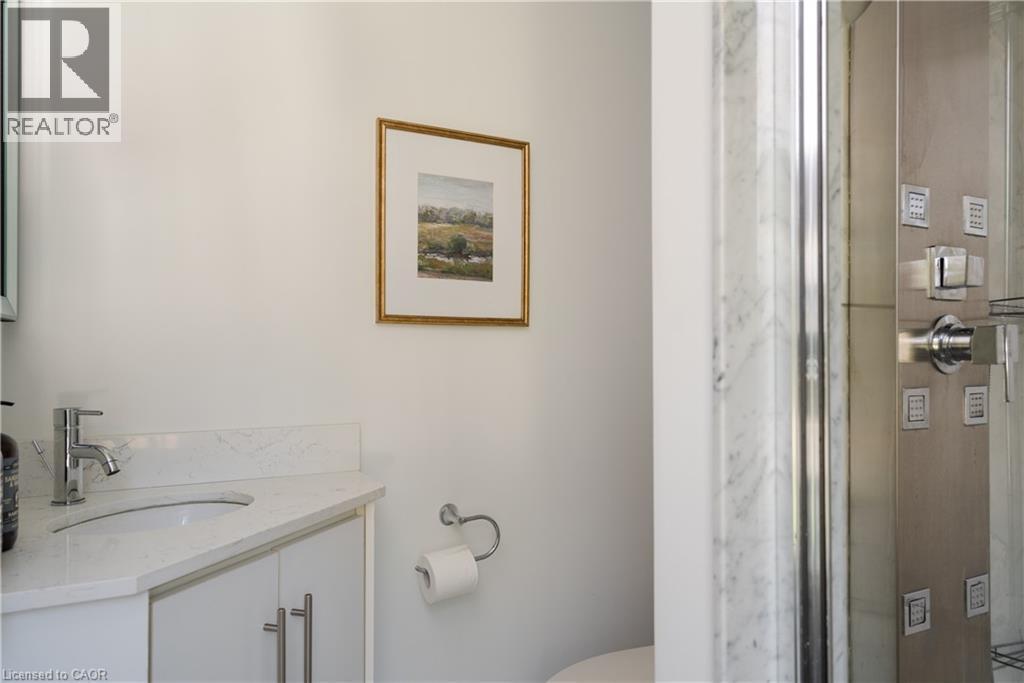 Vanity with a polished chrome faucet, white countertop, and white cabinetry with stainless steel pulls - 50 Norway Avenue, Hamilton, ON