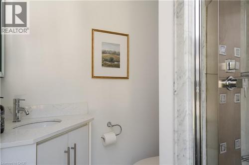 Vanity with a polished chrome faucet, white countertop, and white cabinetry with stainless steel pulls - 50 Norway Avenue, Hamilton, ON 