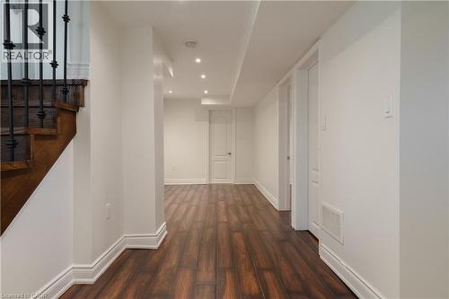 Wood-finish flooring, recessed ceiling lighting, crisp white walls, and a staircase with wrought iron balusters - 50 Norway Avenue, Hamilton, ON 