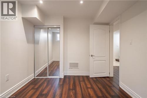 Wood-finish flooring with white baseboards, recessed ceiling lighting, and a white interior door - 50 Norway Avenue, Hamilton, ON 