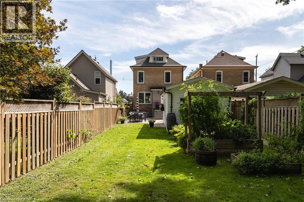 Expansive backyard featuring a manicured lawn, mature trees, and wooden fencing - 50 Norway Avenue, Hamilton, ON
