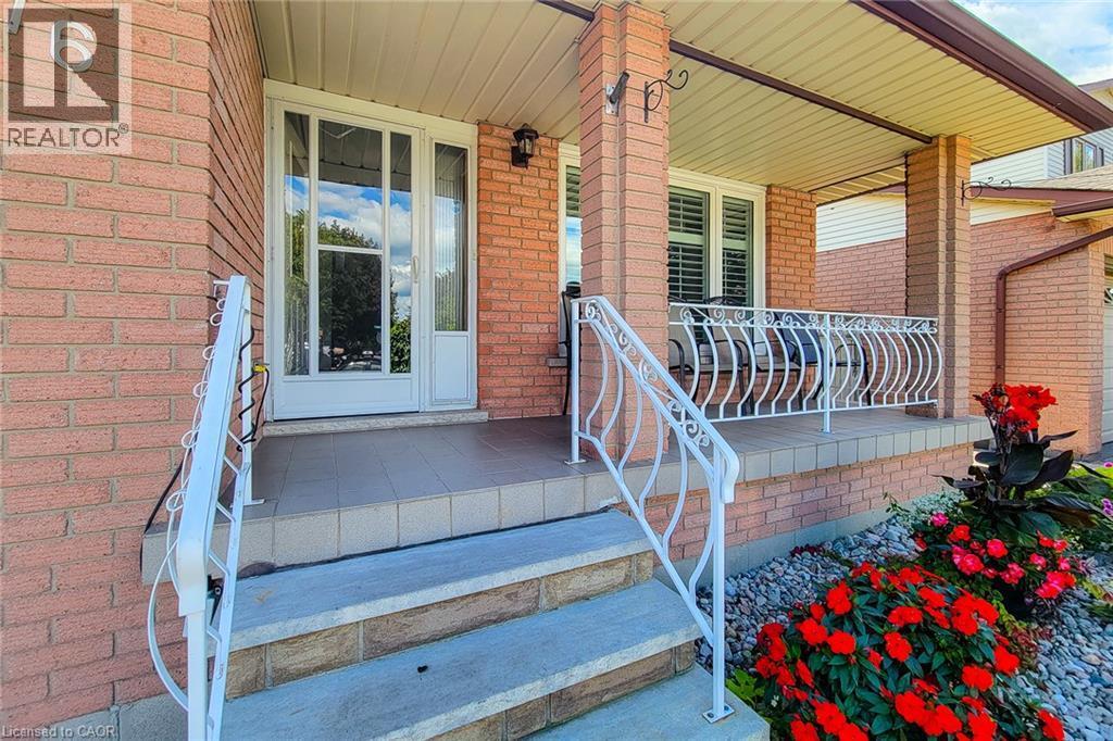 Brick exterior featuring a covered porch, decorative white railings, and a tiled entryway - 276 Greencedar Drive, Hamilton, ON