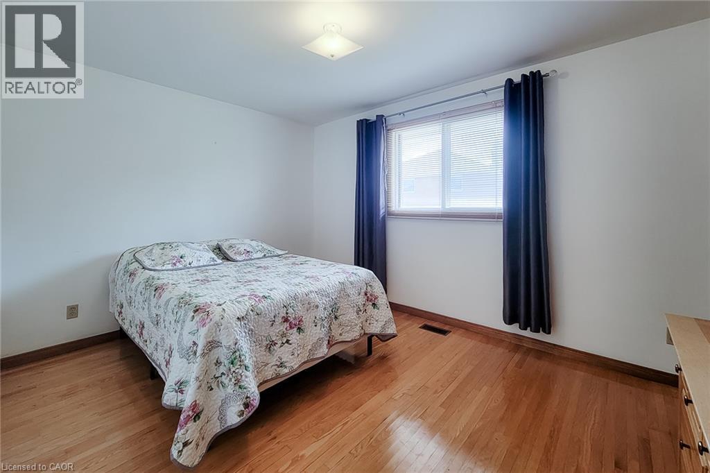 Light-filled room featuring wood-finish flooring and a ceiling-mounted light fixture - 276 Greencedar Drive, Hamilton, ON