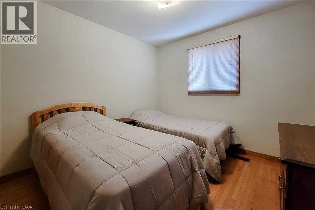 Hardwood flooring throughout, neutral painted walls, and a single window with blinds - 276 Greencedar Drive, Hamilton, ON