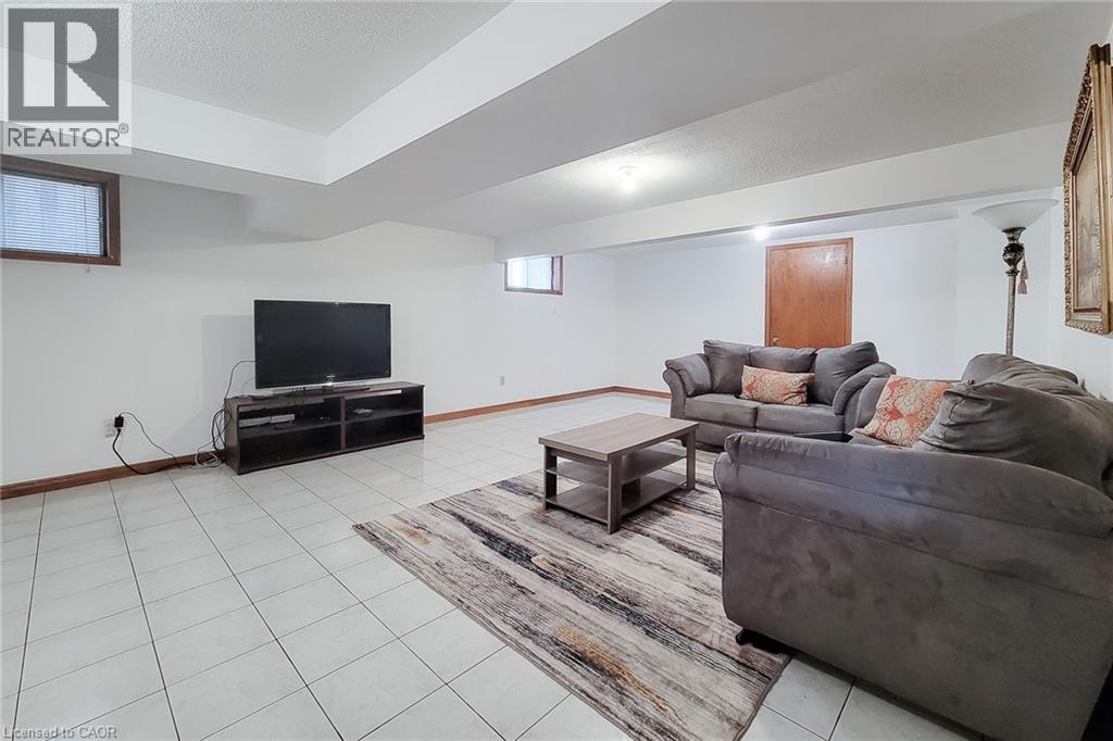 Spacious room featuring white tile flooring, white walls, and a recessed ceiling area - 276 Greencedar Drive, Hamilton, ON