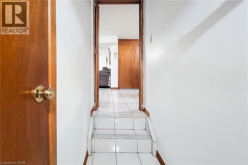 White tile flooring leading to a short staircase with white tile treads and risers - 276 Greencedar Drive, Hamilton, ON
