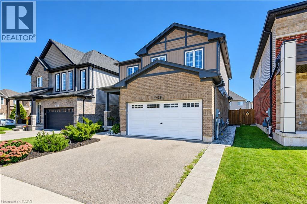 Brick and siding facade with dark trim accents, attached garage with white door, concrete driveway, and well-maintained front landscaping - 428 Freure Drive, Cambridge, ON