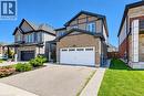 Brick and siding facade with dark trim accents, attached garage with white door, concrete driveway, and well-maintained front landscaping - 428 Freure Drive, Cambridge, ON 