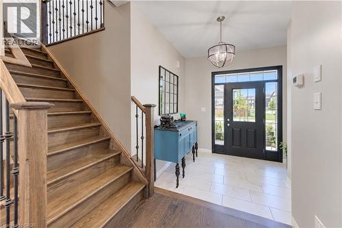 Wide entry featuring large format tile flooring, a dark wood-finish staircase with wrought iron balusters, and a black front door with sidelights - 428 Freure Drive, Cambridge, ON 