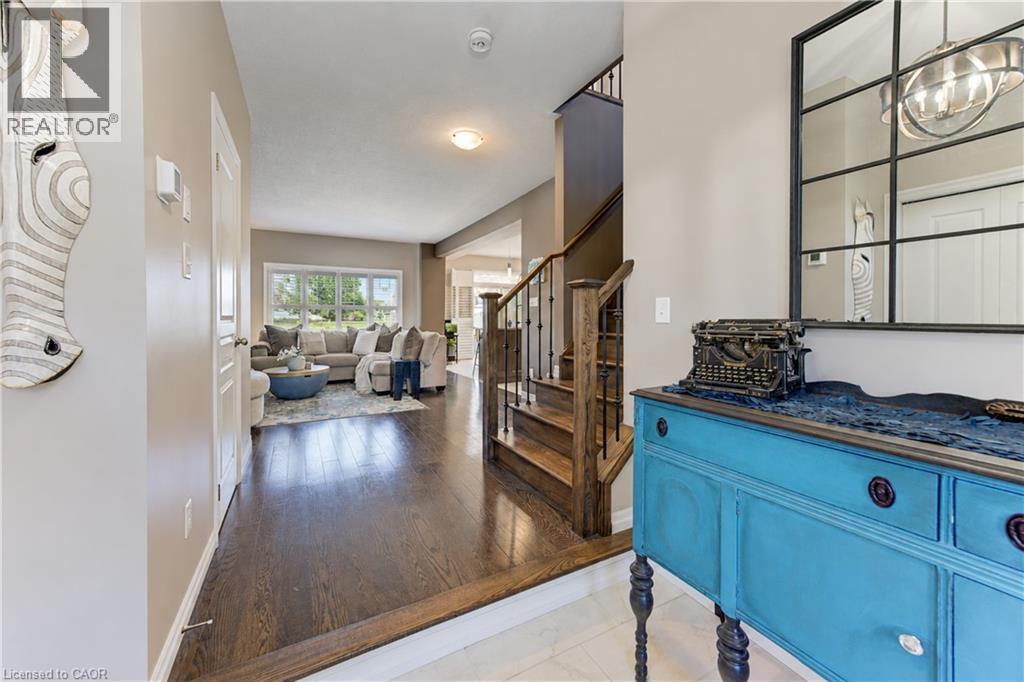 Hardwood flooring, natural light through large windows, staircase with dark wood and metal balusters, ceiling-mounted lighting - 428 Freure Drive, Cambridge, ON