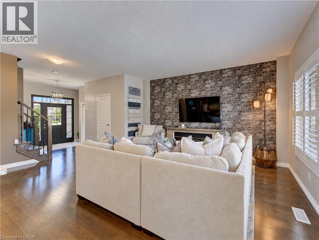 Hardwood flooring throughout, a decorative brick accent wall, white window shutters, and a front entry with a transom window and sidelights - 428 Freure Drive, Cambridge, ON