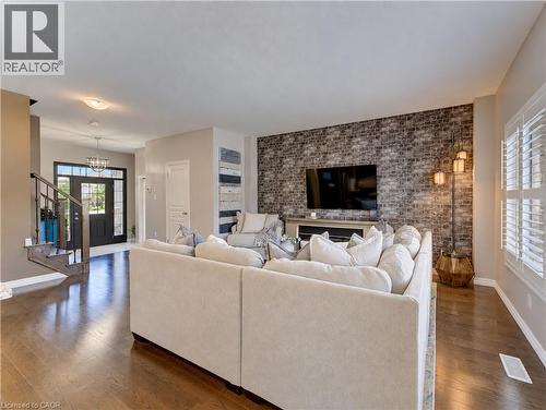Hardwood flooring throughout, a decorative brick accent wall, white window shutters, and a front entry with a transom window and sidelights - 428 Freure Drive, Cambridge, ON 