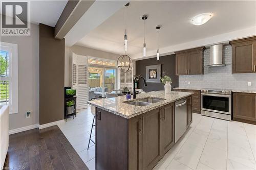 Kitchen featuring a central island with dual sinks, stone countertop, and pendant lighting - 428 Freure Drive, Cambridge, ON 
