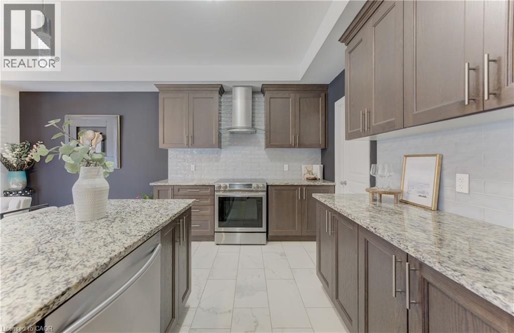 Kitchen featuring a large island, stainless steel appliances, granite countertops, wood-finish cabinetry, and a tile backsplash - 428 Freure Drive, Cambridge, ON