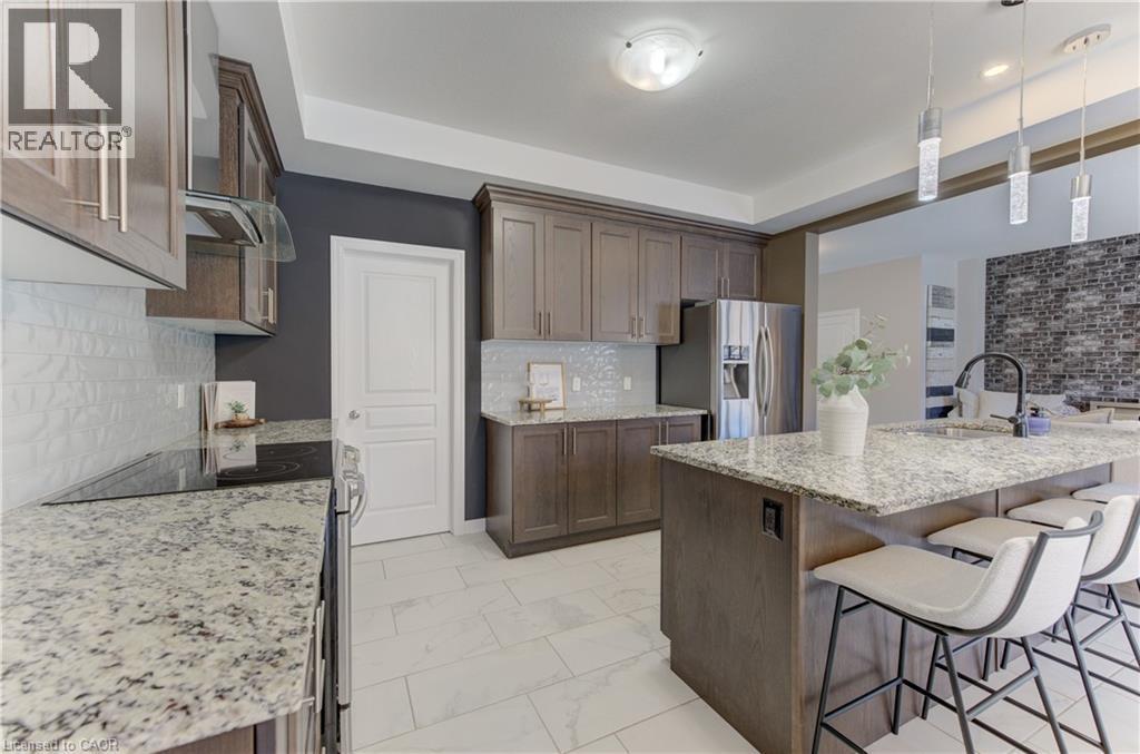 Wood-finish cabinetry, stainless steel appliances, granite countertops, and a tile backsplash - 428 Freure Drive, Cambridge, ON