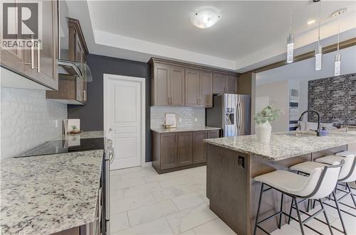 Wood-finish cabinetry, stainless steel appliances, granite countertops, and a tile backsplash - 428 Freure Drive, Cambridge, ON 