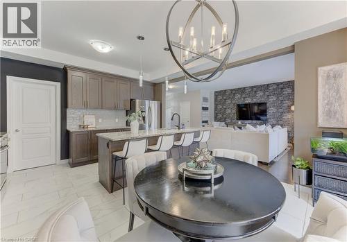 Open-concept kitchen and living area featuring a large center island with seating, dark wood cabinetry, and stainless steel appliances - 428 Freure Drive, Cambridge, ON 