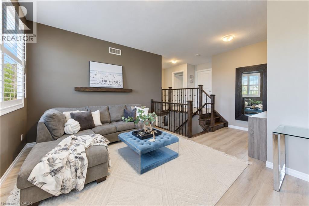Open-concept living area featuring light wood-finish flooring, a built-in wall shelf, and plantation shutters - 428 Freure Drive, Cambridge, ON