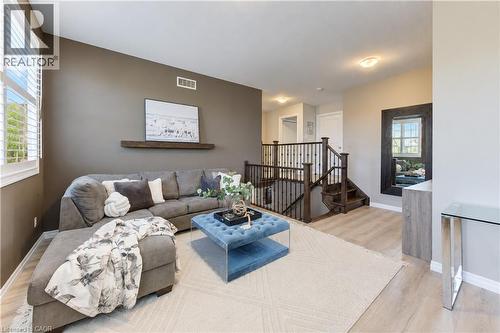 Open-concept living area featuring light wood-finish flooring, a built-in wall shelf, and plantation shutters - 428 Freure Drive, Cambridge, ON 