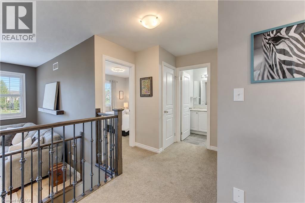 Carpeted hallway with painted walls, a wrought iron and wood-finish railing, and dome lighting fixtures - 428 Freure Drive, Cambridge, ON