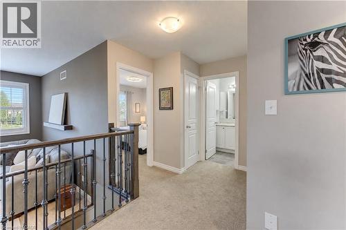Carpeted hallway with painted walls, a wrought iron and wood-finish railing, and dome lighting fixtures - 428 Freure Drive, Cambridge, ON 