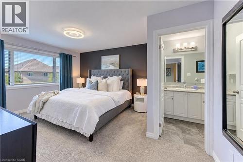 Wall-to-wall carpeting, expansive window with blinds, modern ceiling light fixture, and an attached three-light vanity - 428 Freure Drive, Cambridge, ON 