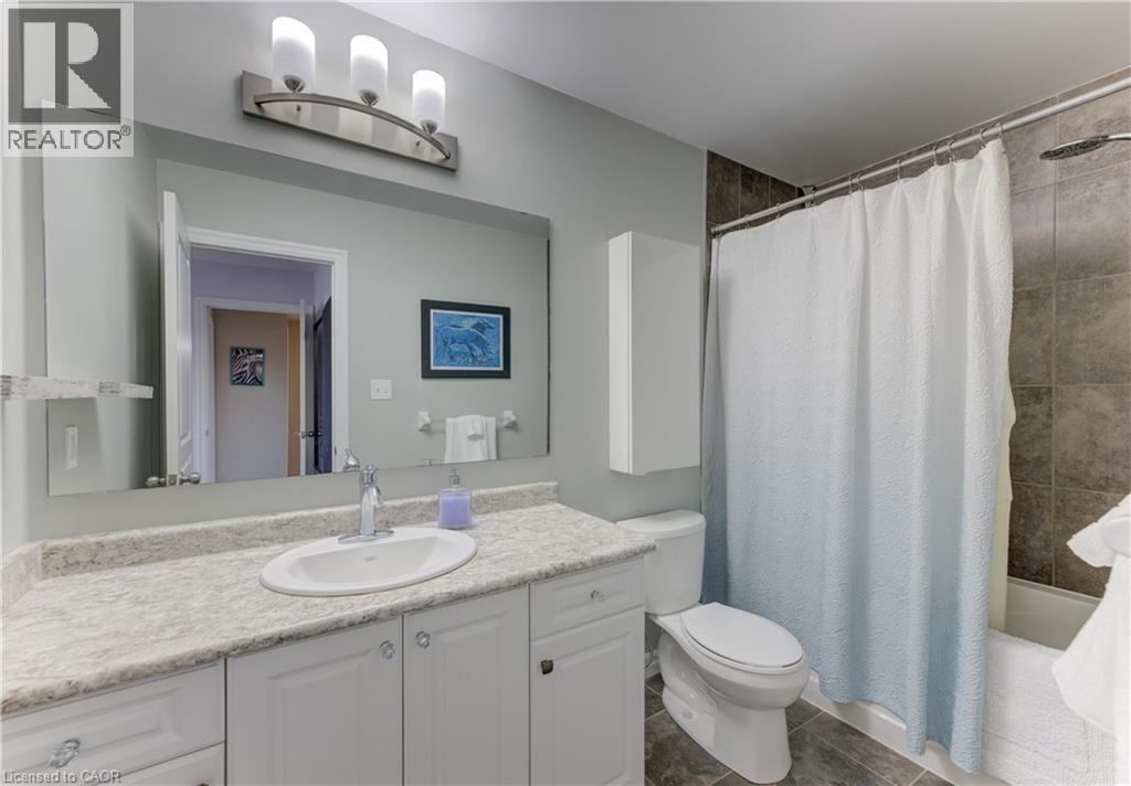 Vanity with an integrated sink, expansive wall mirror, and a three-light fixture - 428 Freure Drive, Cambridge, ON