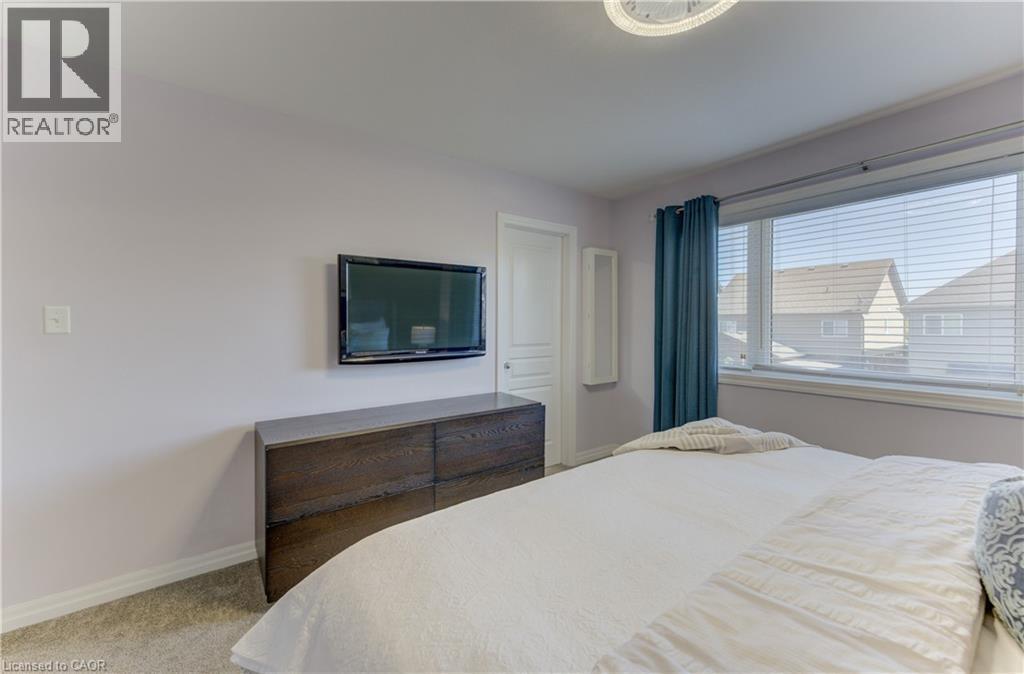 Carpeted flooring, window with blinds, wall-mounted television, built-in shelving, and a flush mount ceiling light fixture - 428 Freure Drive, Cambridge, ON